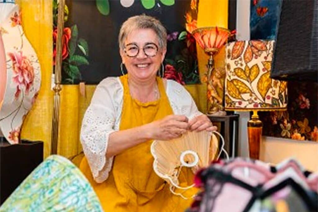 Sylvie Lemarchand souriante dans sa boutique, entourée d’abat-jours et de tissus