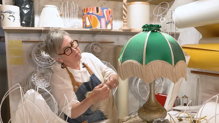 Sylvie Lemarchand posant une frange sur un abat-jour vert dans son atelier de Cormeilles